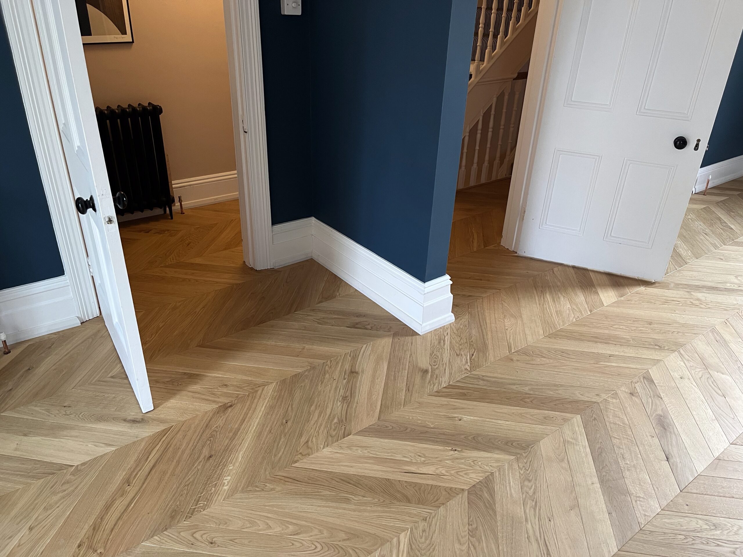 Chevron parquet flooring in living room with blue walls
