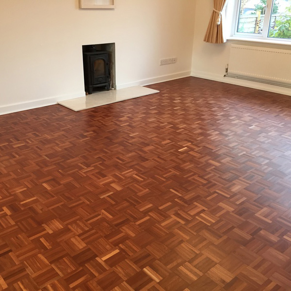 Parquet floor after refinishing process whole living room area with fireplace in the middle.