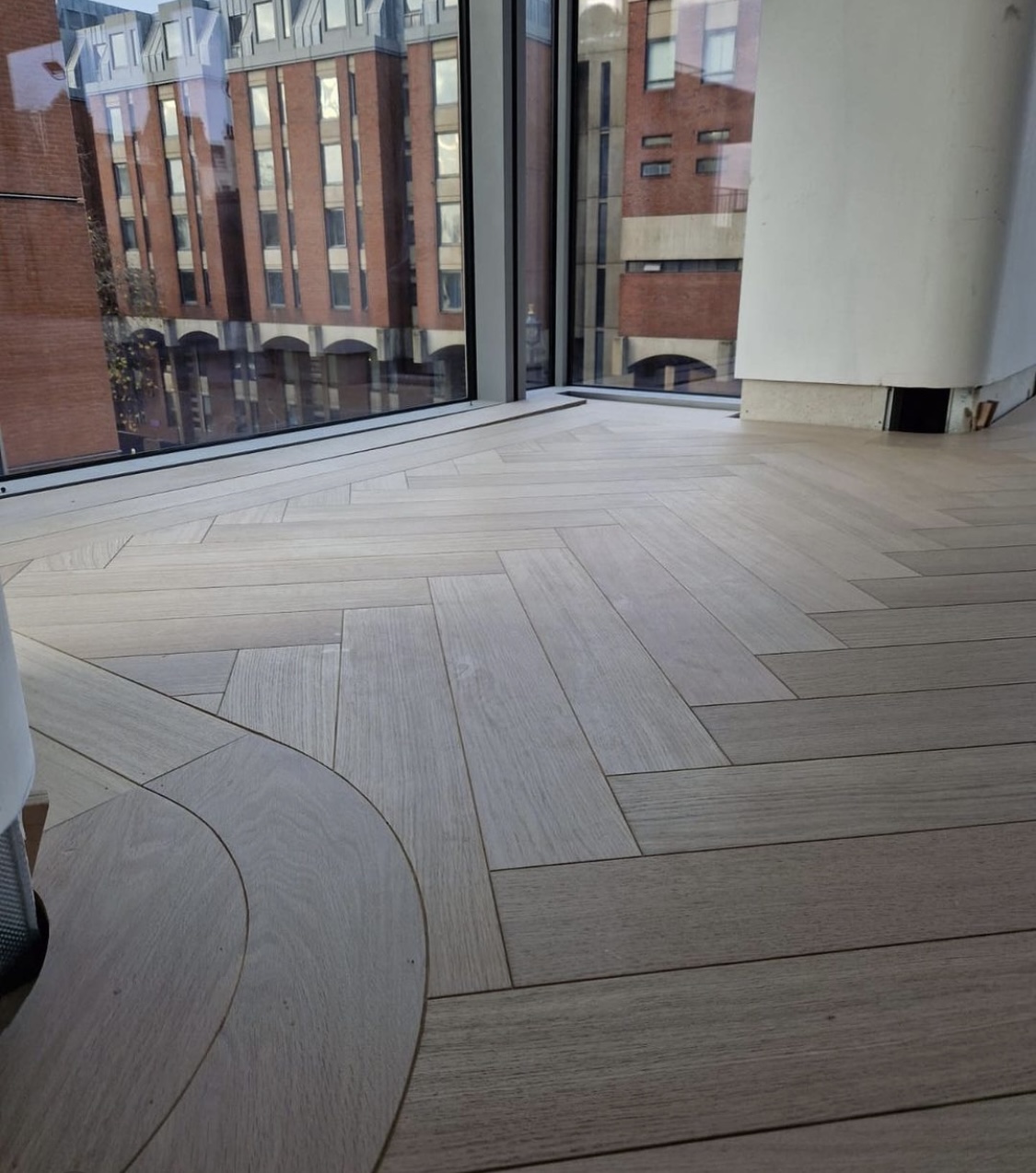 Complex wood floor design with parquet and straight flooring going around corners at the edge.