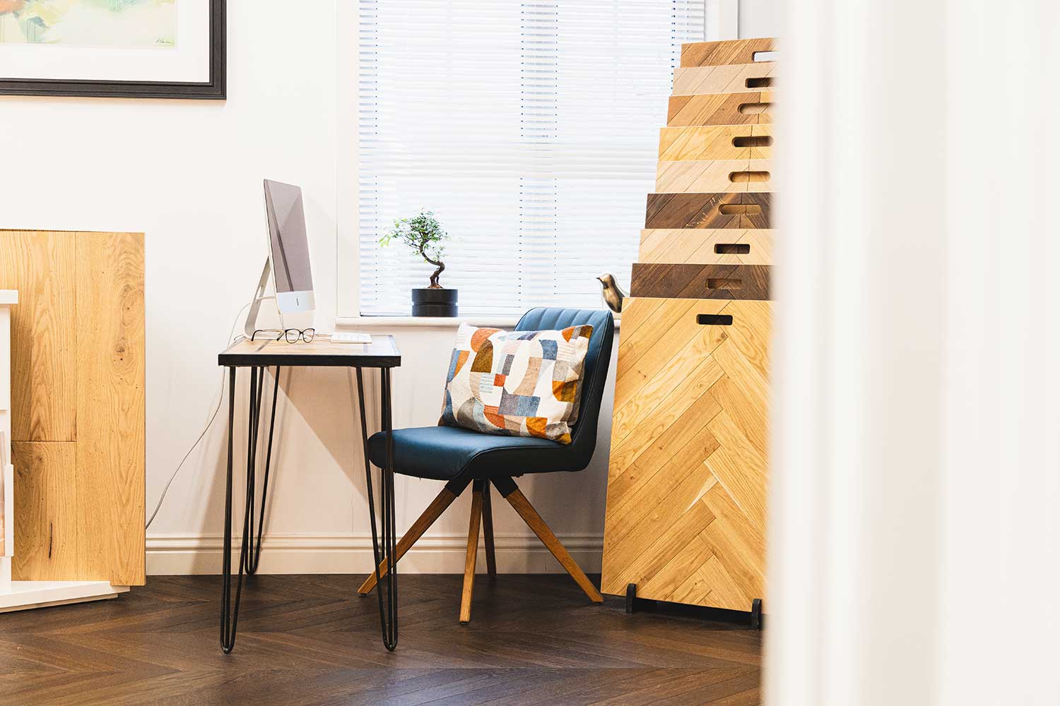 Showroom image of a table with computer on top with wood flooring samples next to it.