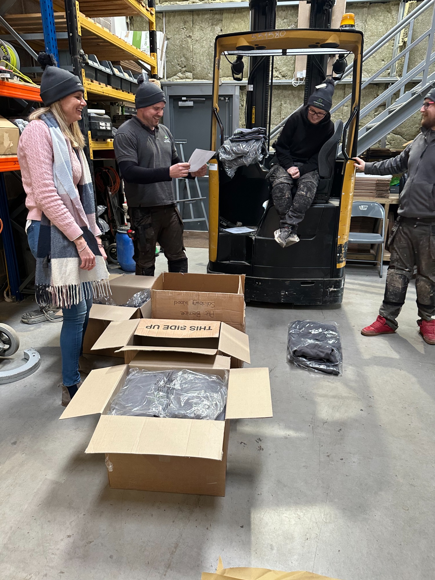 Four salisbury wood floor team members opening boxes in a warehouse revealing clothing.