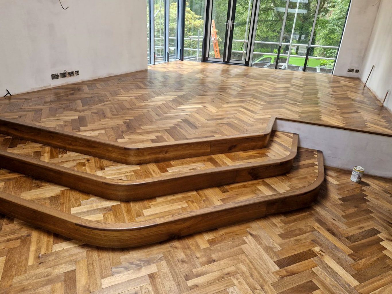 Stair cladding installed in large front room area with parquet pattern.