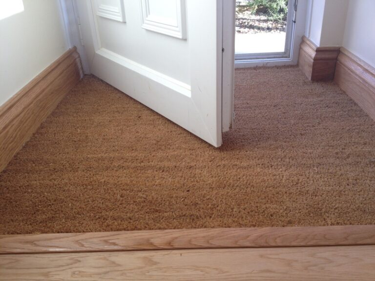 Trim work at front door around coir mat.